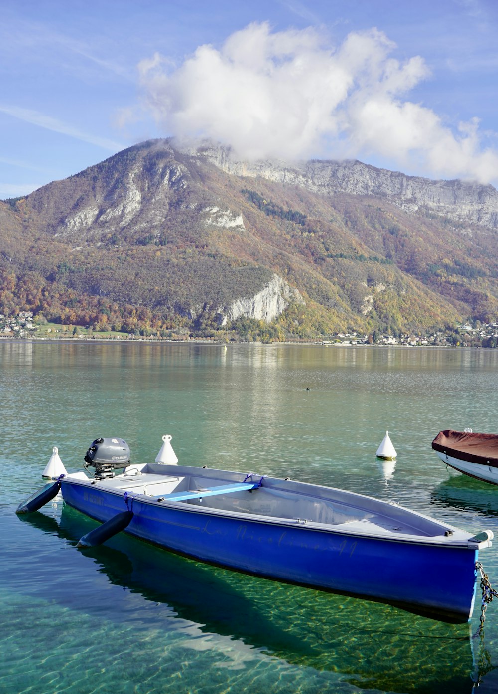 Un bateau bleu assis au sommet d’un lac à côté d’une montagne