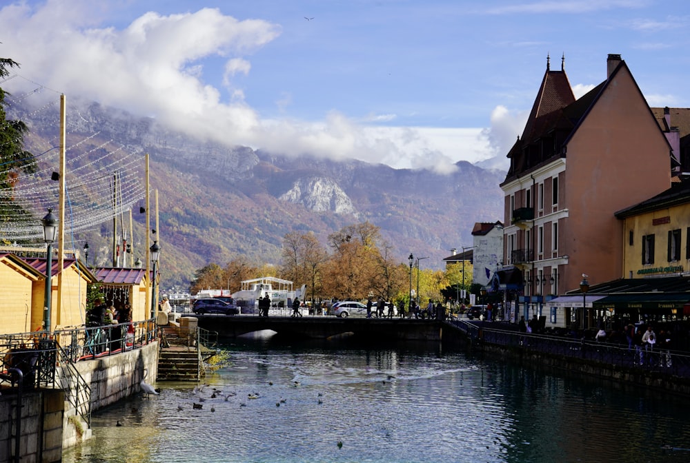 a river running through a small town with mountains in the background