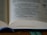 An open book displaying text on its pages. The pages are filled with printed words in a serif font, with one section of the text highlighted in blue ink. The image focuses on the text and shows the spine with a blue bookmark ribbon partially visible.