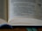 An open book displaying text on its pages. The pages are filled with printed words in a serif font, with one section of the text highlighted in blue ink. The image focuses on the text and shows the spine with a blue bookmark ribbon partially visible.