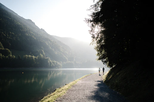 A serene morning jogger stretching by a sunlit lake, embodying health and vitality.