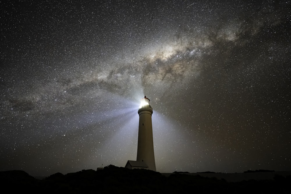 a lighthouse under a night sky filled with stars