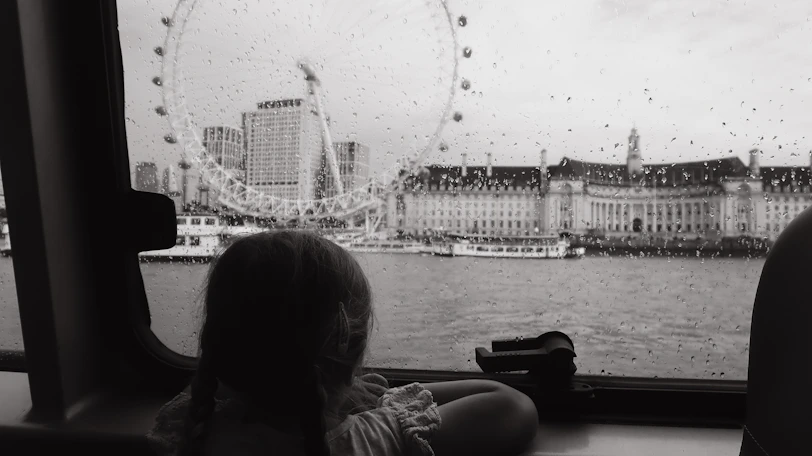 a little girl looking out a window at a ferris wheel