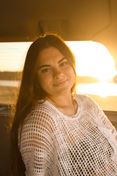 A female driver smiling warmly while helping a woman into a car at dusk.