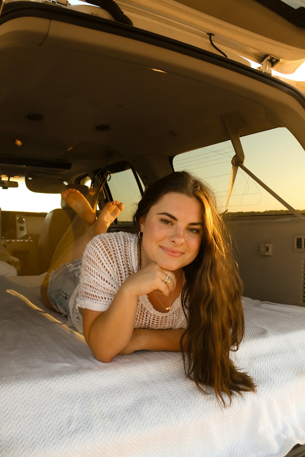 a woman laying on a bed in the back of a car