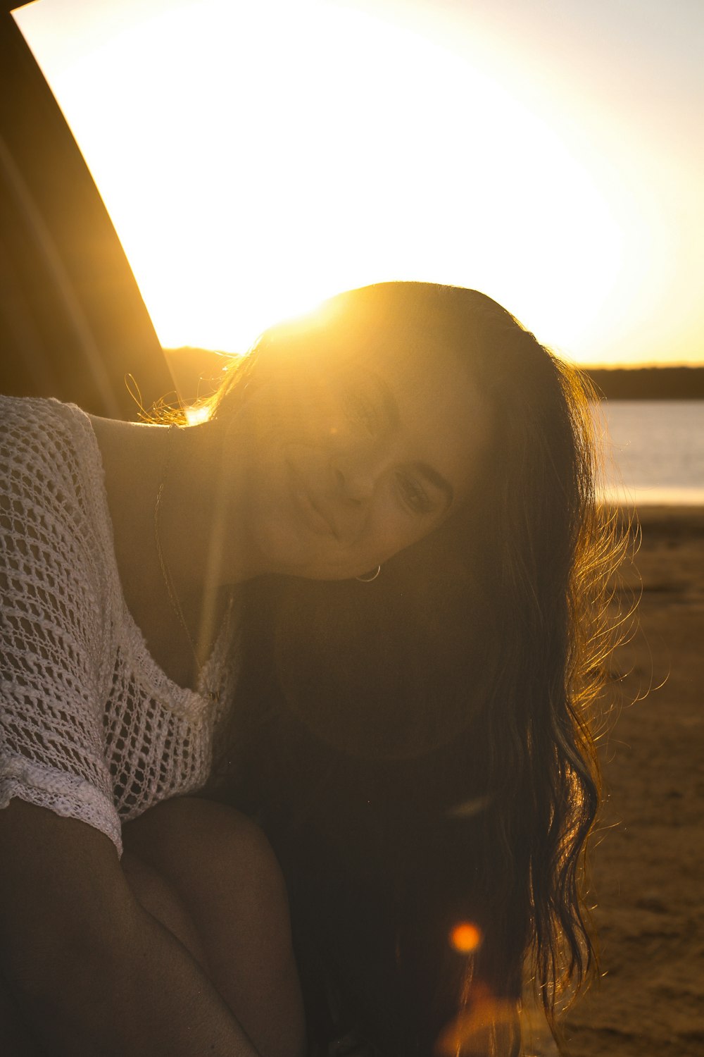 a woman sitting in the back of a car on a beach