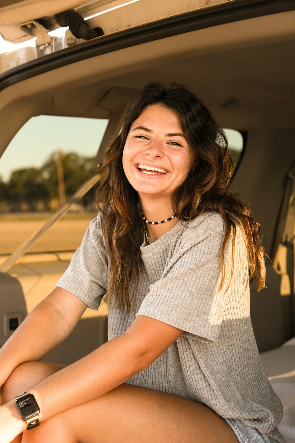 a woman sitting in the back of a car smiling