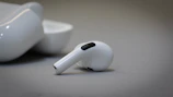 Close-up of a matte black wireless earbud case resting on a soft white surface.
