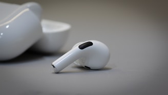 A sleek 1xplus wireless earbud resting on a glowing electric blue surface.