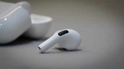 Close-up of a matte black wireless earbud case resting on a soft white surface.