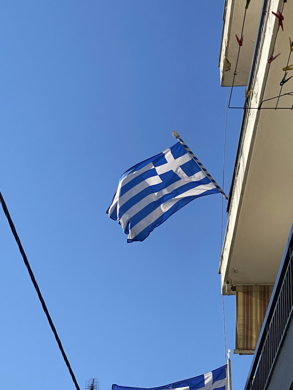 Un drapeau grec flottant devant un bâtiment