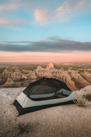 A rugged rooftop tent set up on a mountain overlook at sunset
