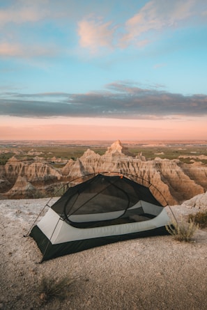 A rugged rooftop tent set up on a mountain overlook at sunset