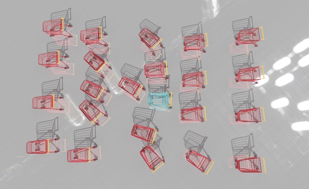 Multiple shopping carts are arranged in a neat pattern on a reflective surface. Most carts are red with one distinct blue cart in the center.