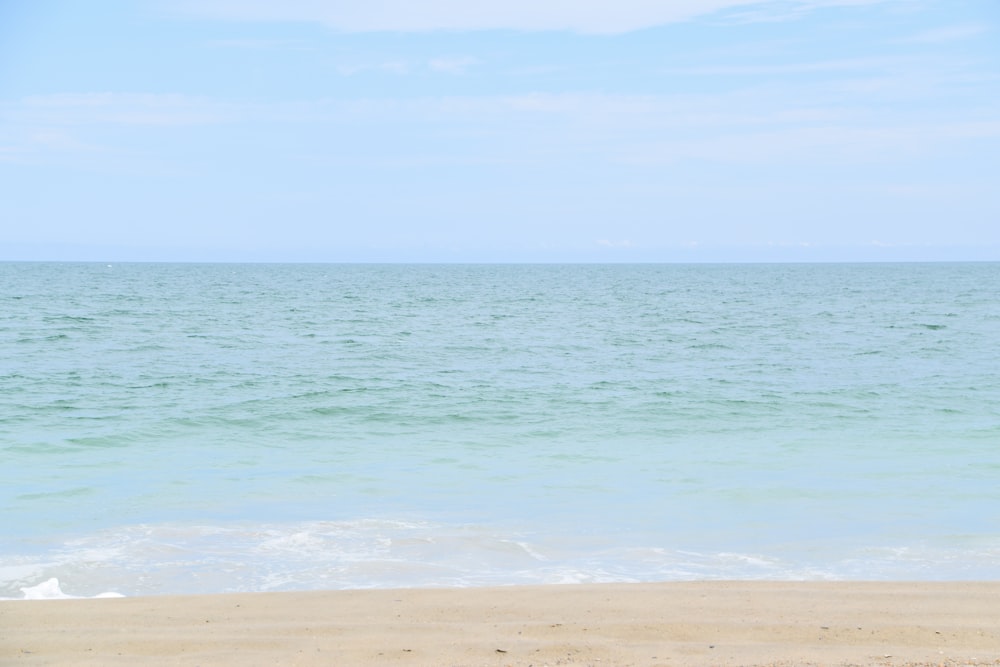 a person walking on the beach with a surfboard