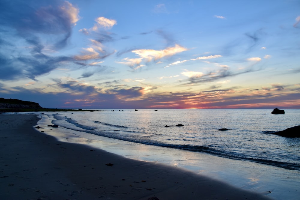 the sun is setting over the water at the beach