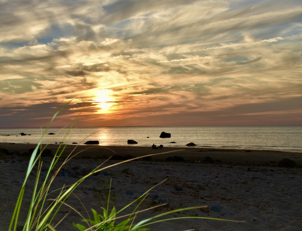 the sun is setting over the ocean on the beach