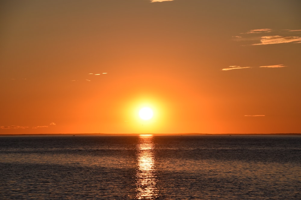 a large body of water with a sunset in the background