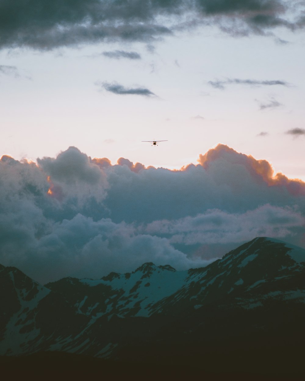 a helicopter flying over a mountain covered in clouds
