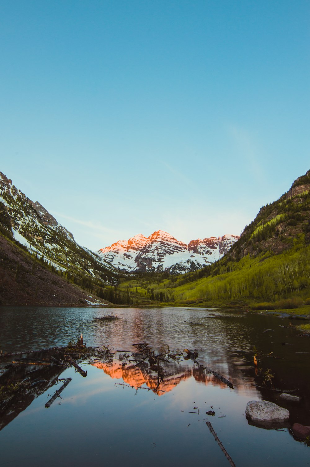 a lake surrounded by mountains with snow on the tops