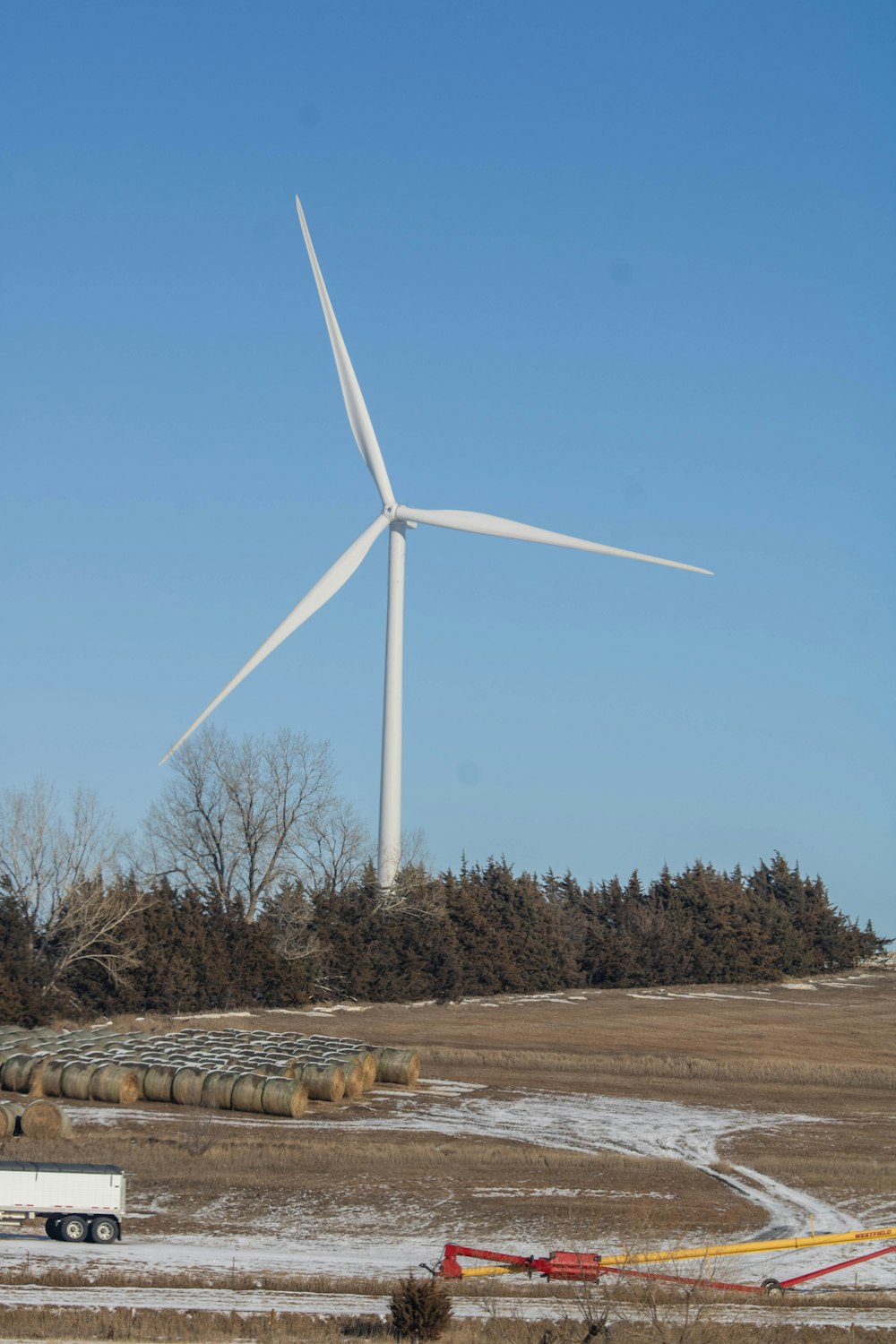 a truck driving down a road past a wind turbine