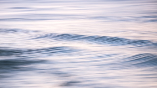 Gentle waves create a serene and calming effect on the water's surface. The soft hues of blue and gray blend seamlessly, reflecting a tranquil atmosphere.