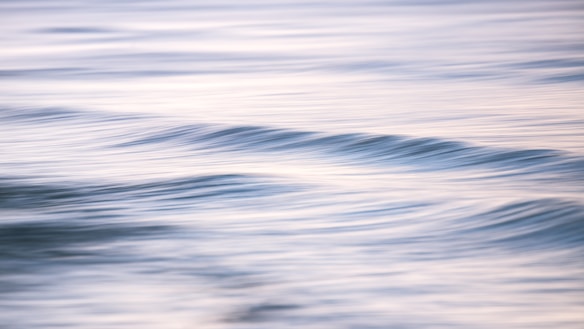 Gentle waves create a serene and calming effect on the water's surface. The soft hues of blue and gray blend seamlessly, reflecting a tranquil atmosphere.