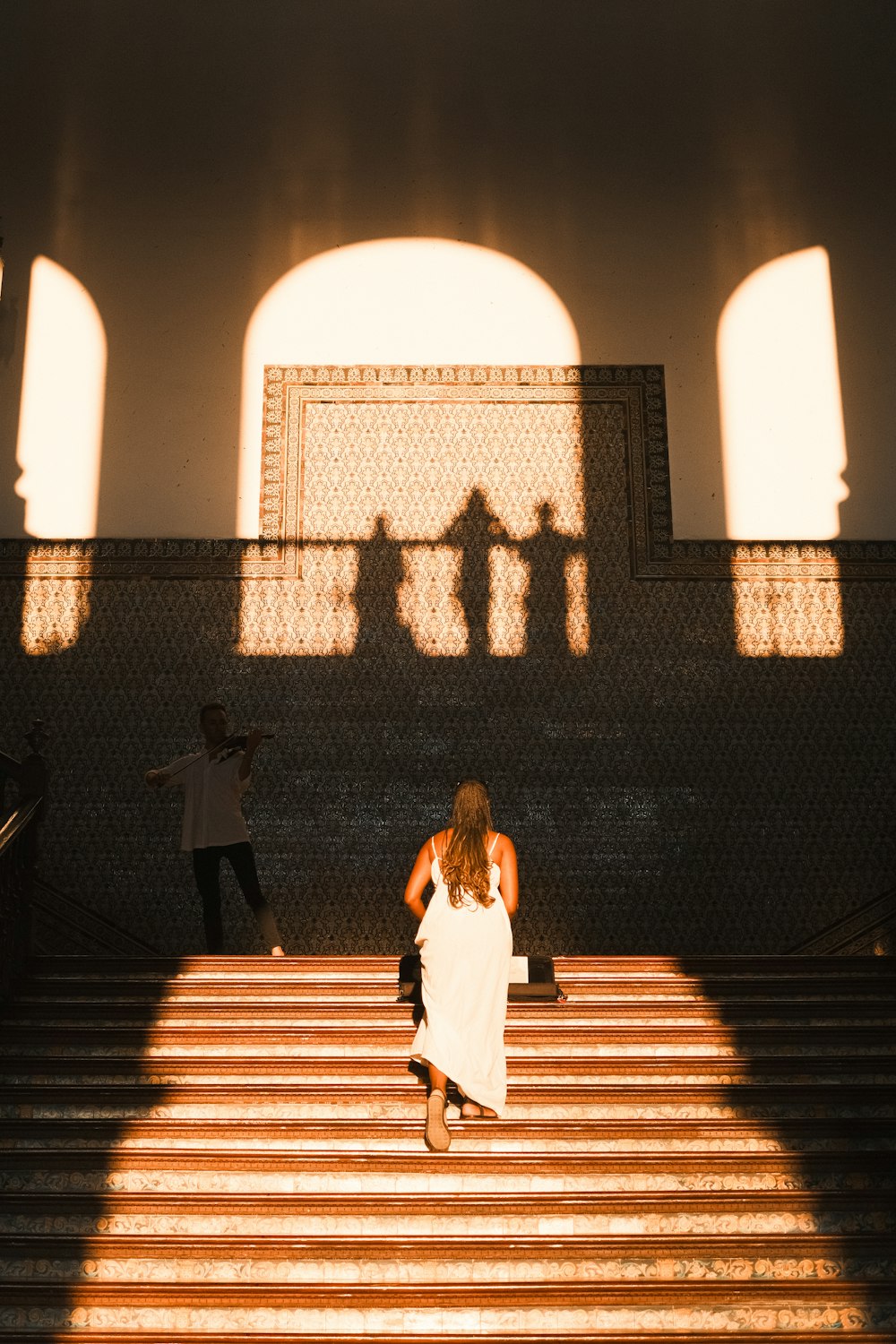 a woman in a white dress walking down some stairs