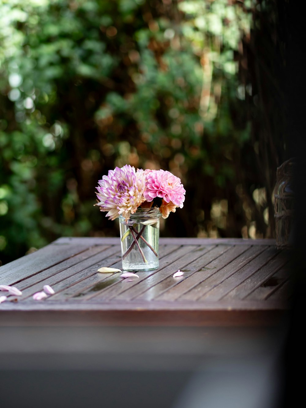 a glass vase filled with pink flowers on a wooden table