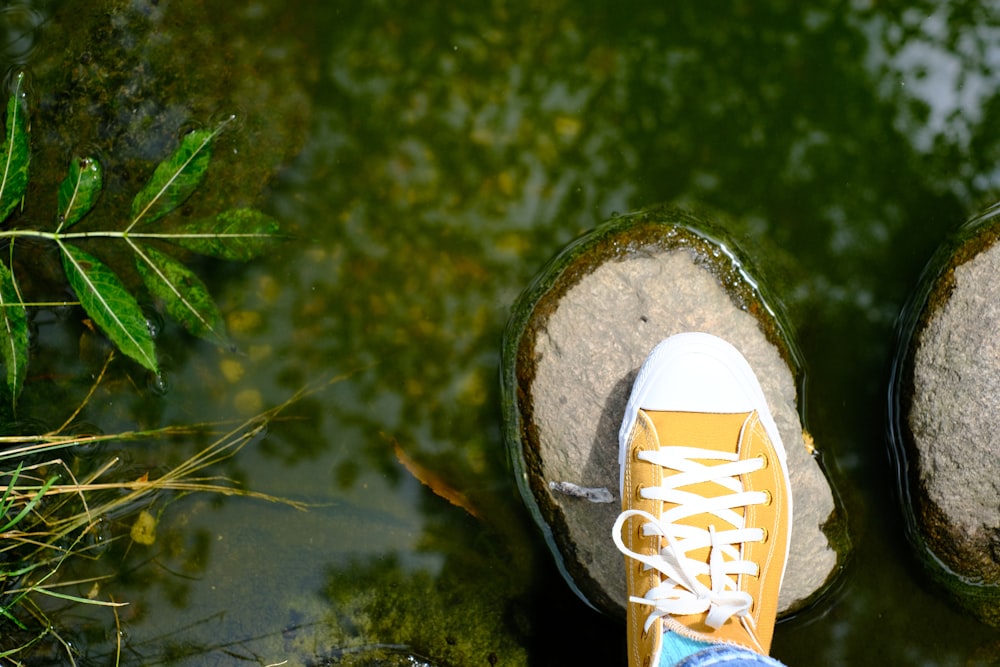 a person standing on top of a rock next to a body of water