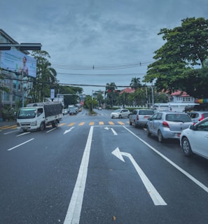 A busy urban street with multiple cars and traffic signals.