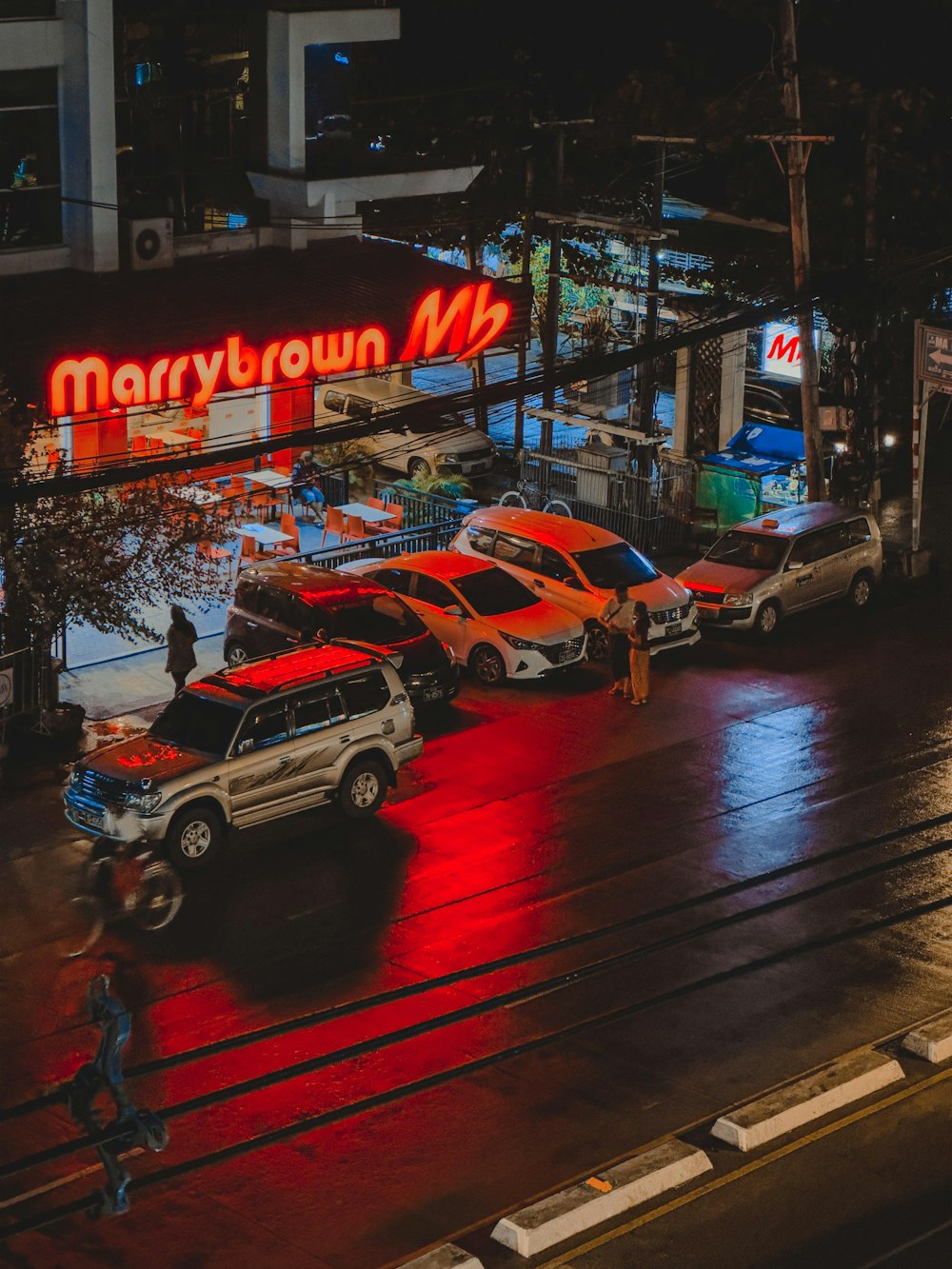 a city street at night with cars parked on the side of the road