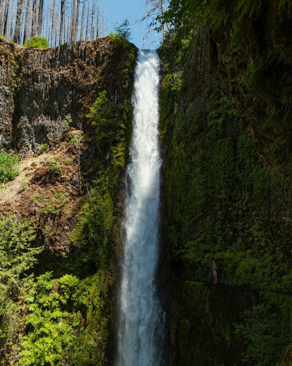 una persona in piedi alla base di una cascata