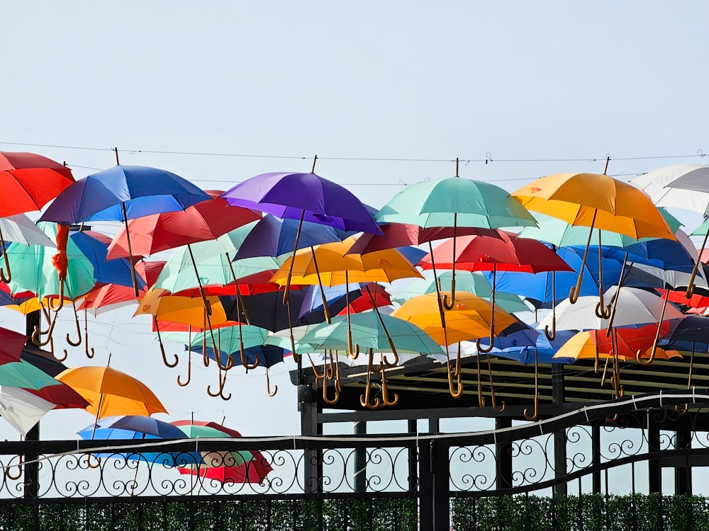 a bunch of colorful umbrellas hanging from a fence