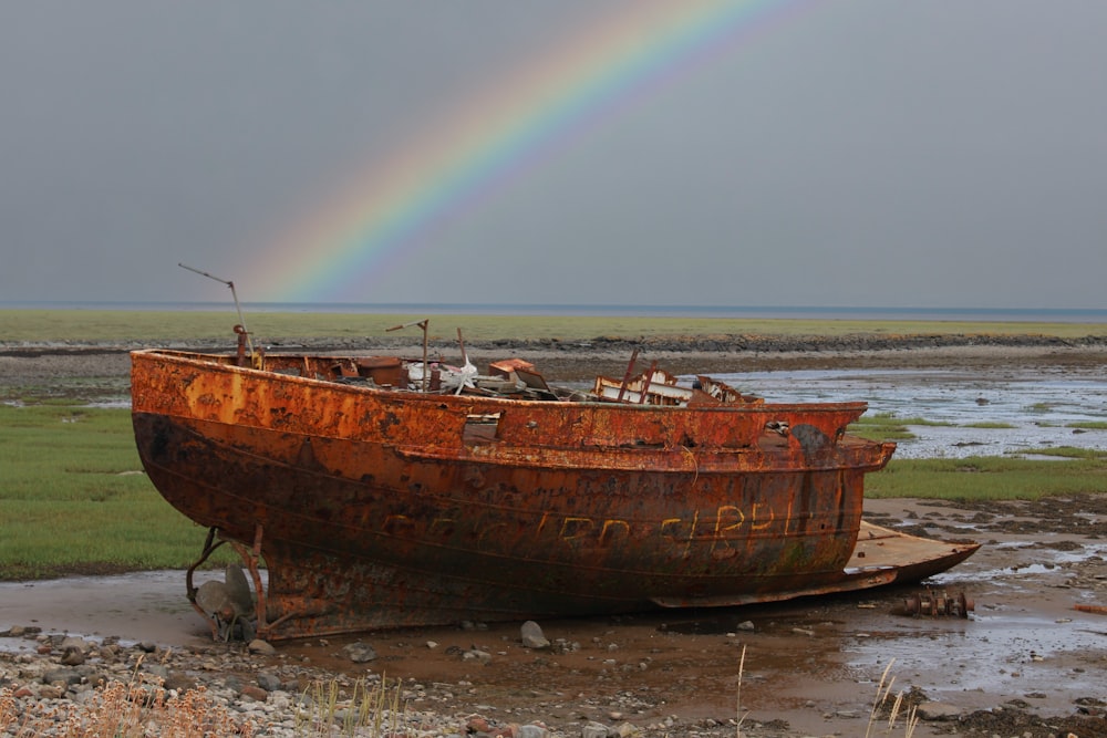 a rusted boat sitting on top of a muddy field
