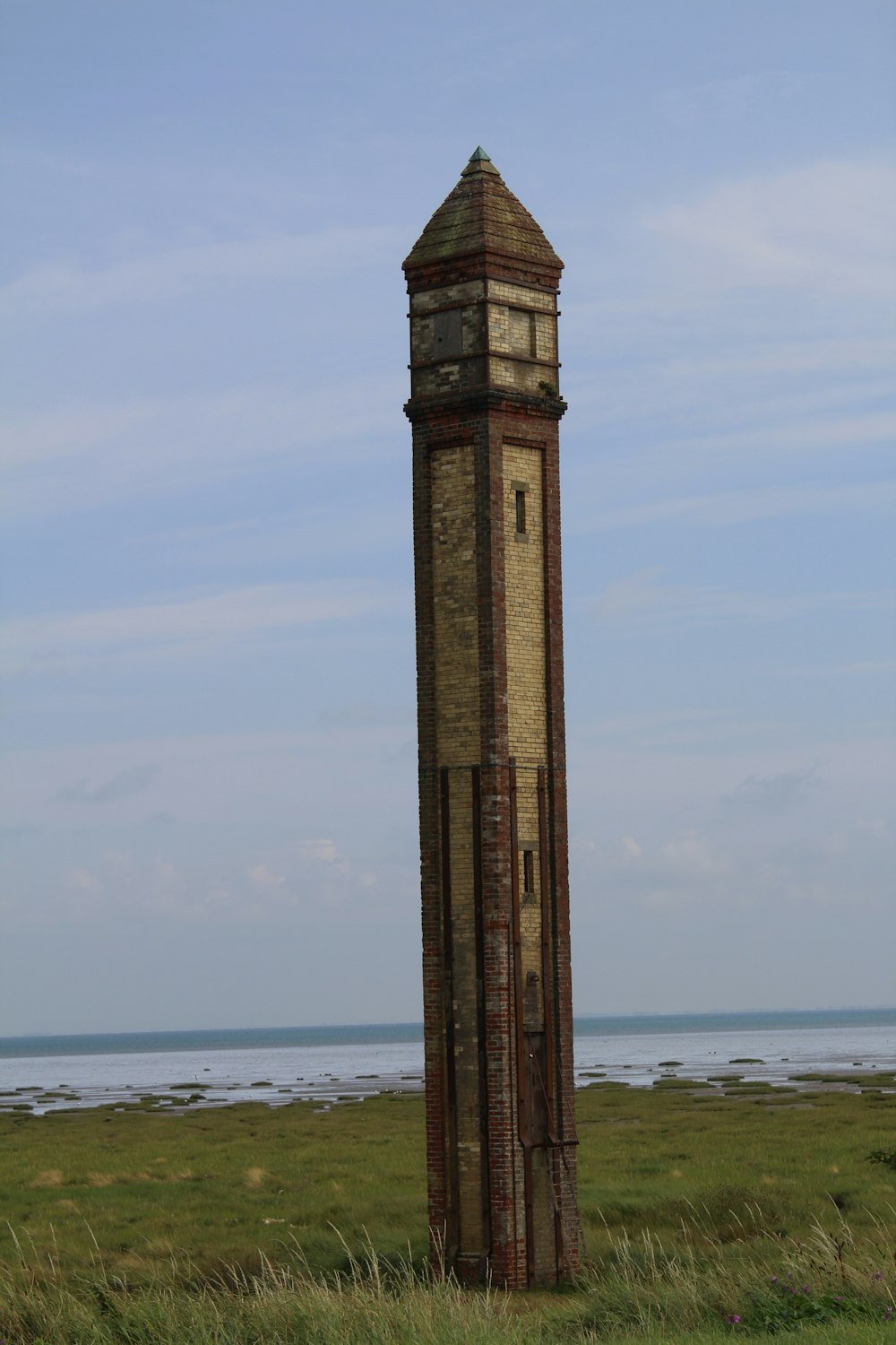 a tall clock tower sitting in the middle of a field