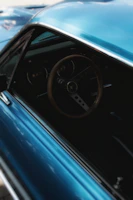 Close-up of a classic car’s polished chrome details and wooden steering wheel.