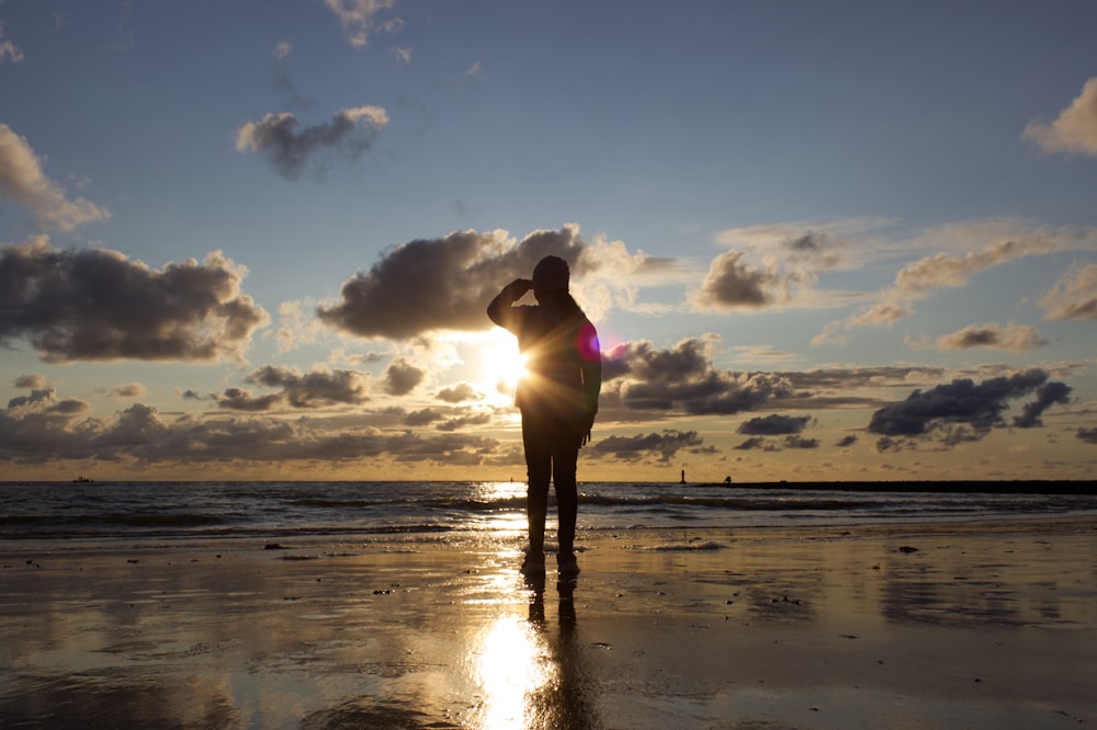Una persona in piedi su una spiaggia al tramonto