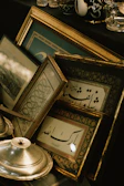 A collection of qurb’s signature gold calligraphy frames arranged elegantly on a cream textured surface.