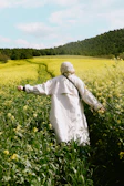 Dilruba Khanam walking through a vibrant mustard field, notebook in hand.