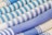 An array of rolled textiles with varying patterns, primarily featuring stripes in shades of blue and white. The fabric textures are visibly detailed, showcasing different weaving styles.