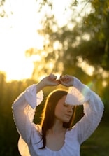 Confident woman standing tall outdoors during golden hour, smiling softly.