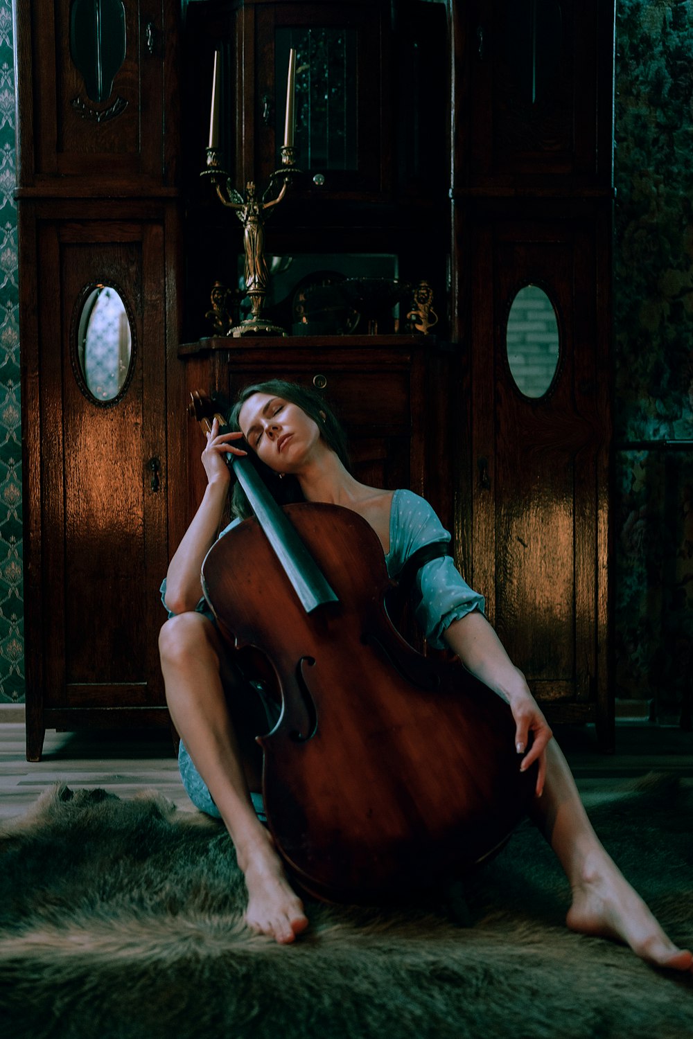 a woman sitting on the floor with a cello