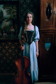 The cellist tuning her instrument while chatting warmly with a wedding planner beside a rustic wooden stage.