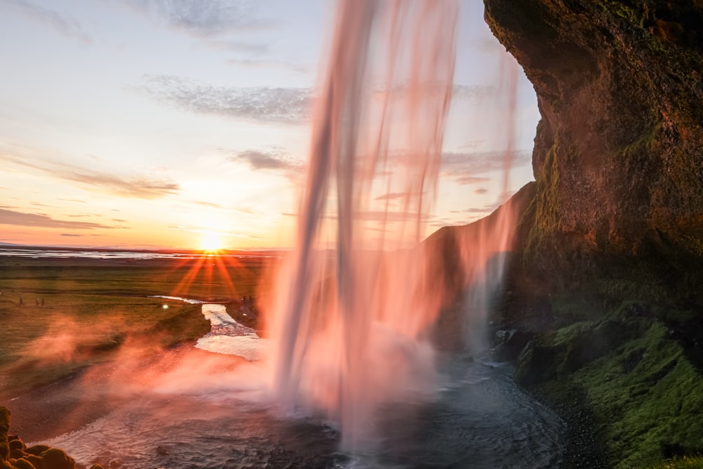 a waterfall with a sunset in the background