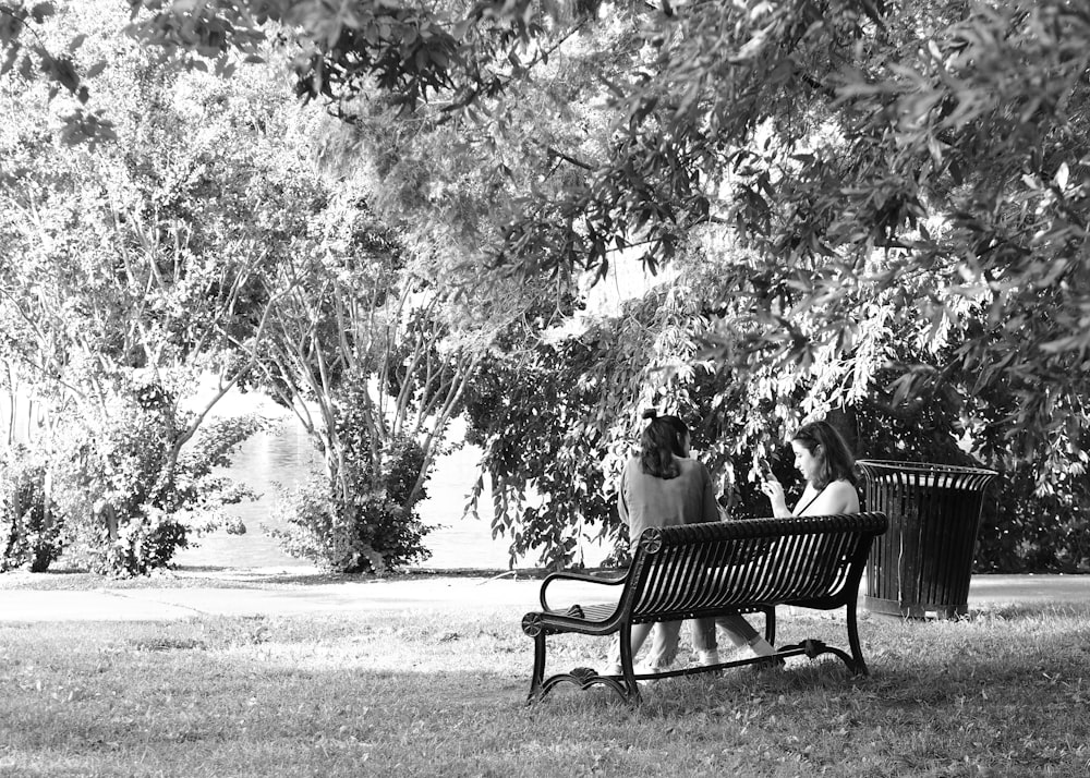 three people sitting on a bench under a tree