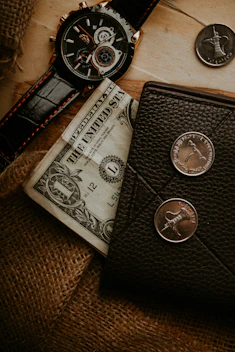 a wallet, watch, and money are on a table