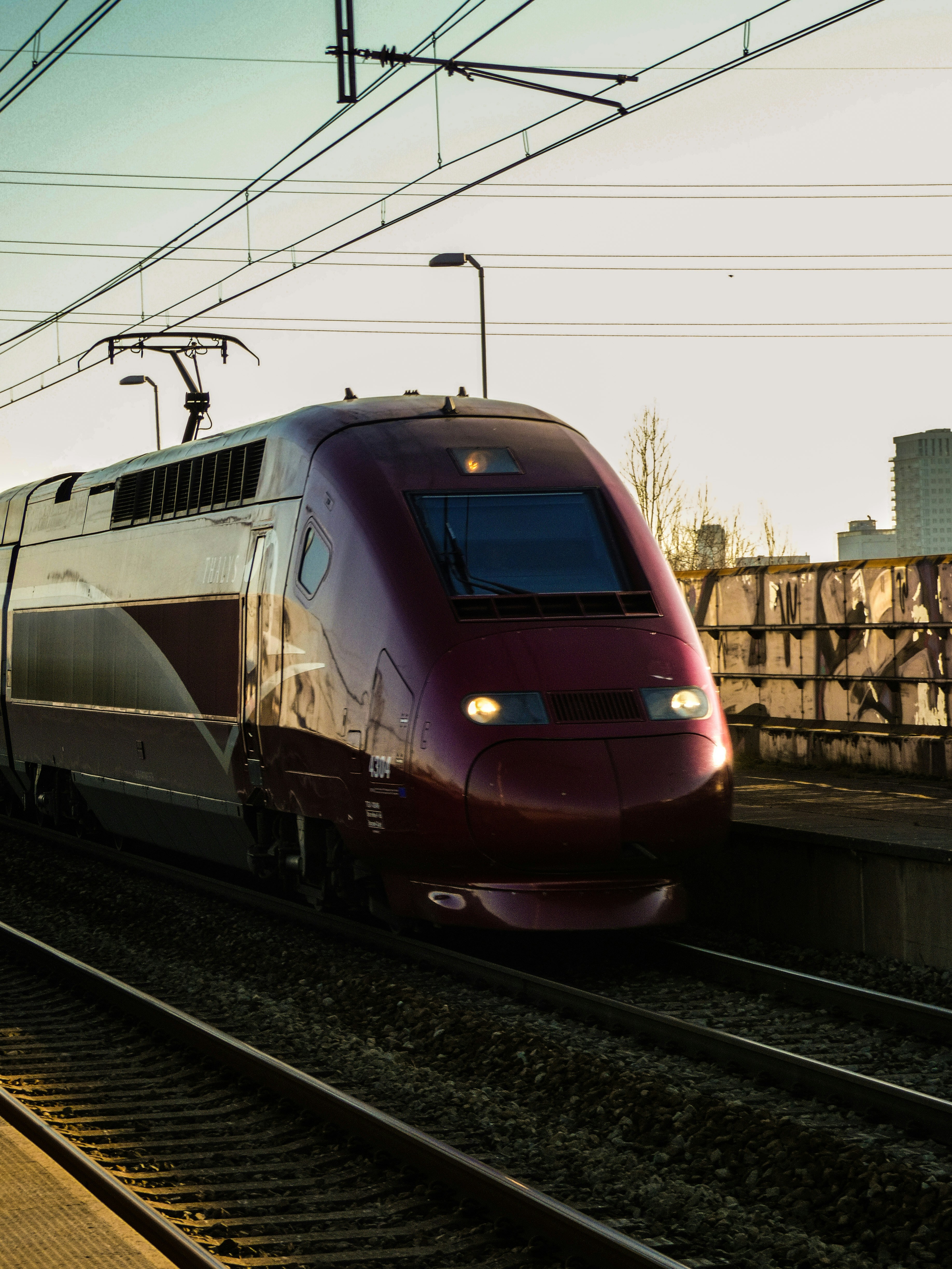 a red train traveling down train tracks next to a tall building
