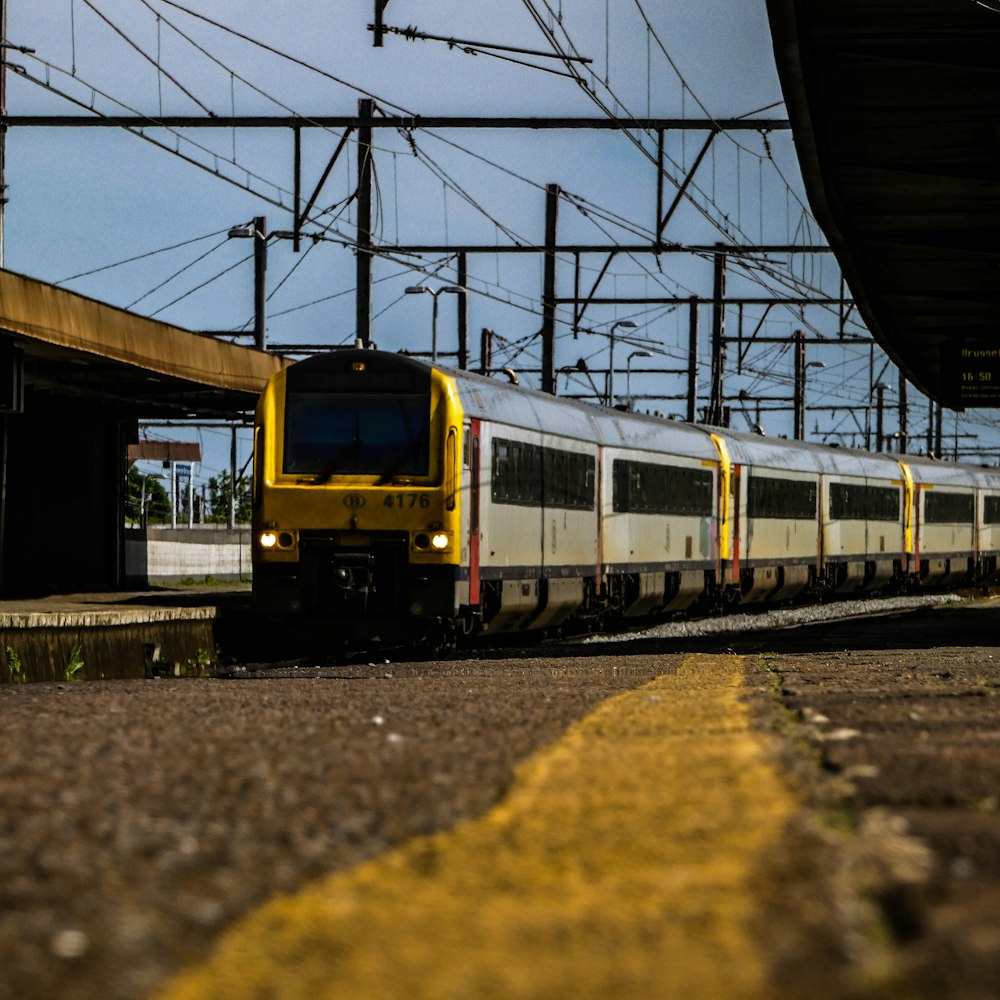 a yellow and white train traveling past a train station