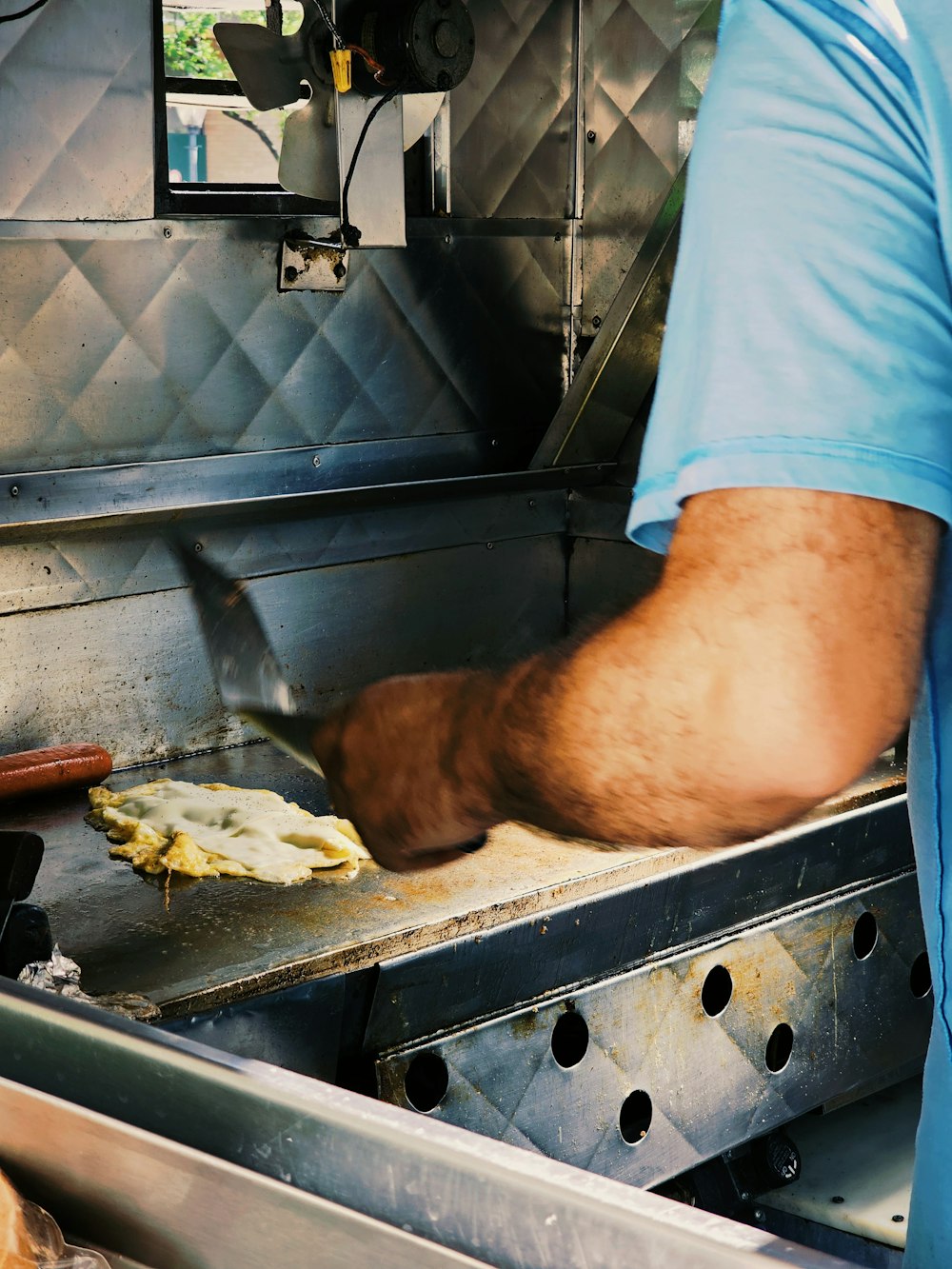 a man in a blue shirt is cooking food on a grill